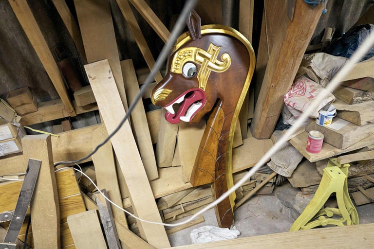 Geschnitzte Pferdekopffigur mit goldenen Akzenten inmitten von Holzmaterialien