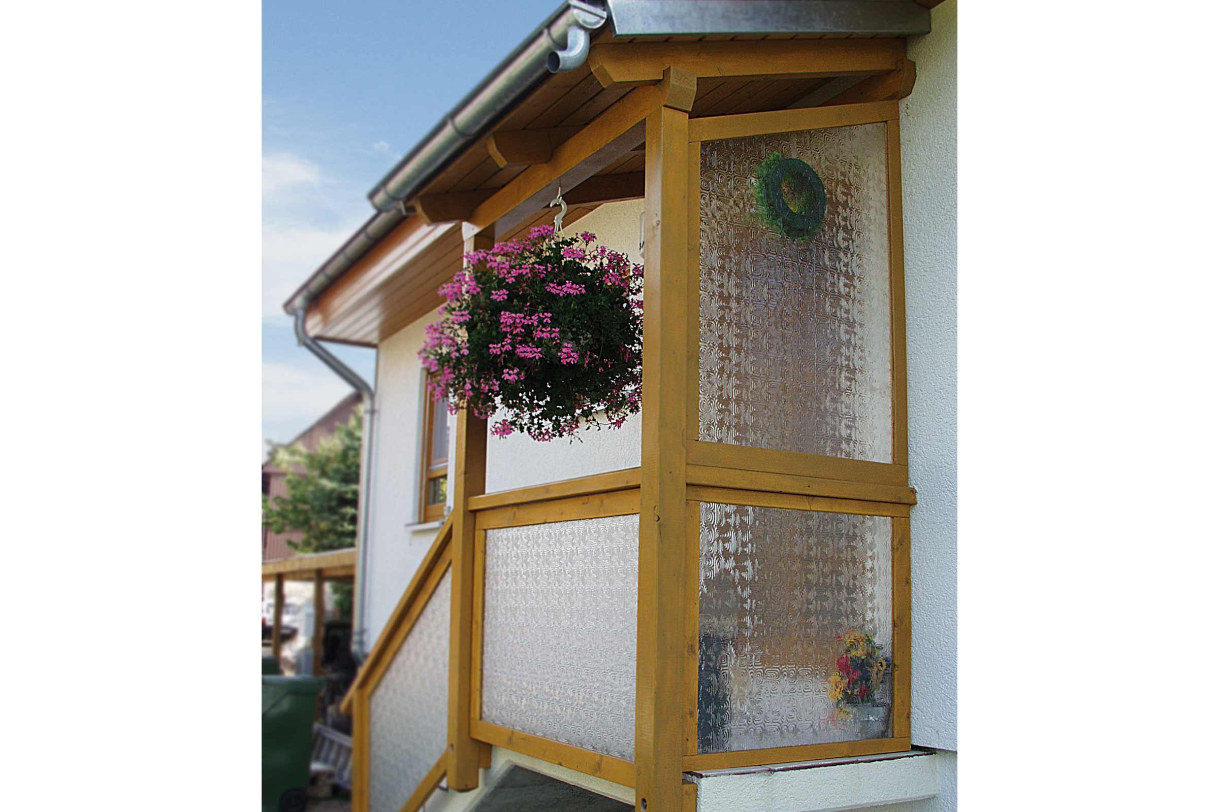 Überdachter Eingangsbereich mit Holzrahmen und Ornamentglas