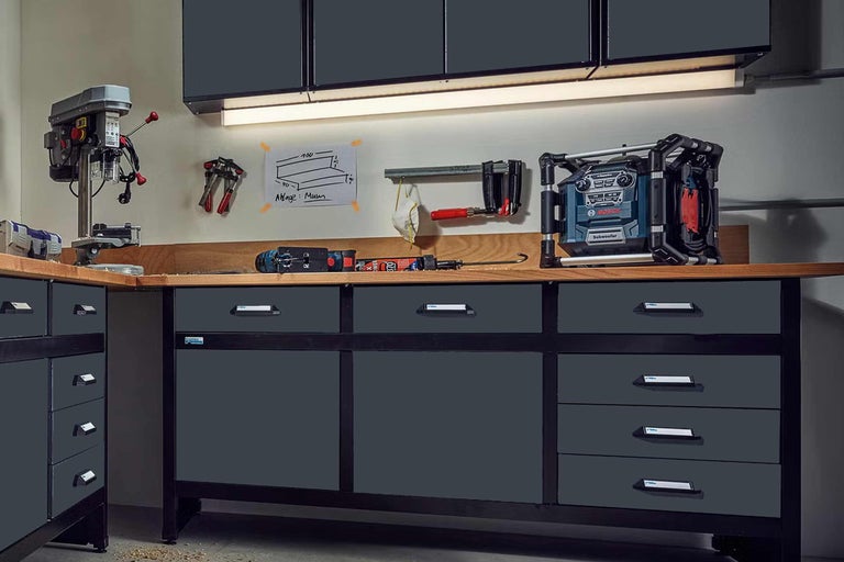 Werkbank mit Schubladen, Bohrmaschine und Baustellenradio in einer Werkstatt