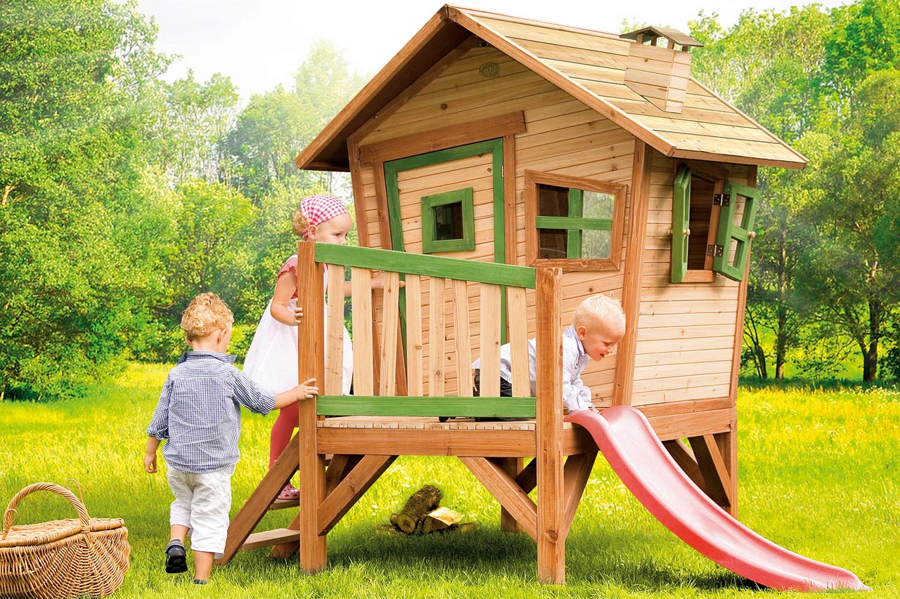 Spielhaus aus Holz mit Rutsche im Garten mit spielenden Kindern