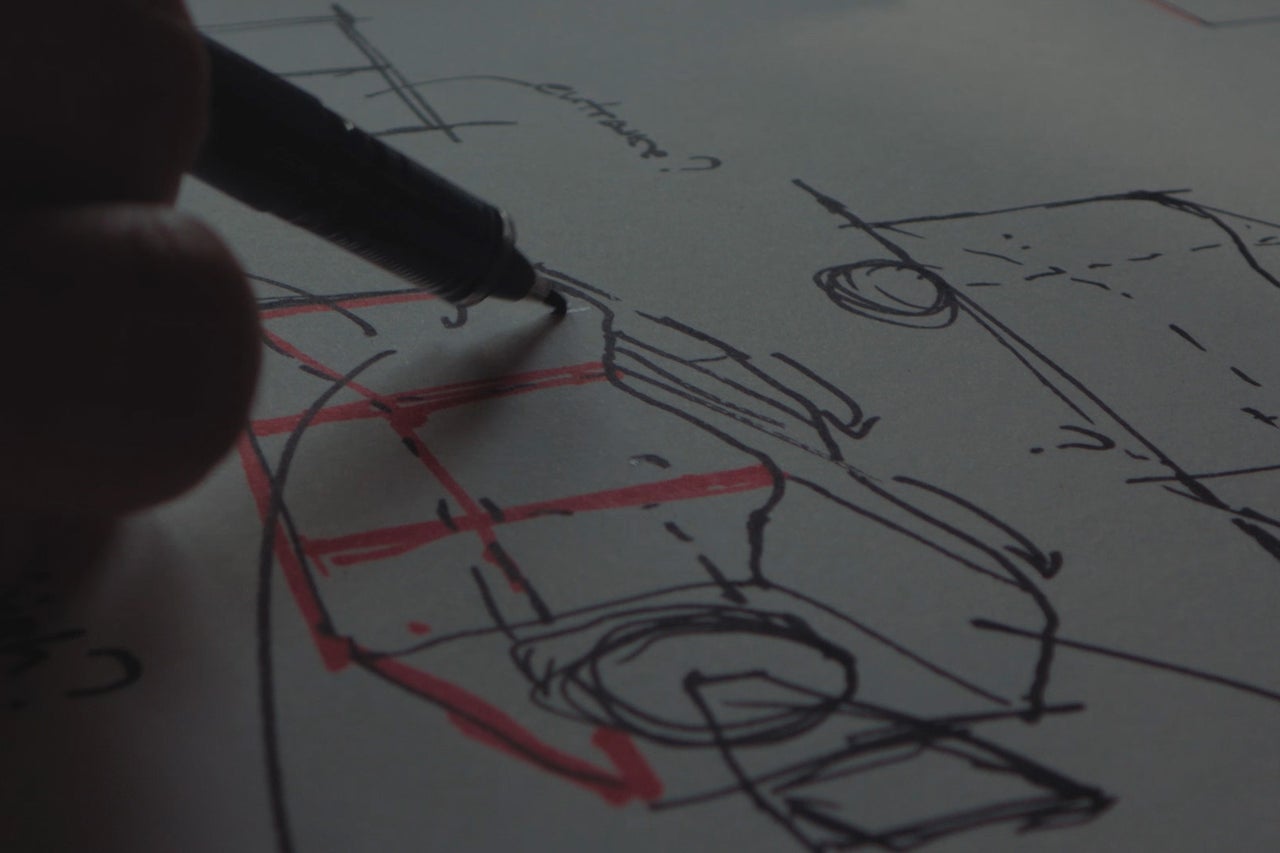 Hand beim Zeichnen einer architektonischen Skizze mit einem Stift auf Papier