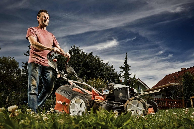 Un homme utilise une tondeuse à gazon dans le jardin.