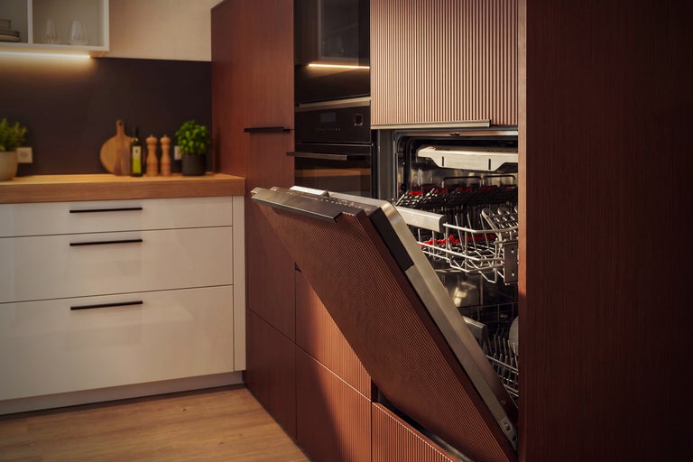 Cuisine équipée moderne avec lave-vaisselle intégré, dont la façade est assortie au design rainuré des meubles de cuisine.