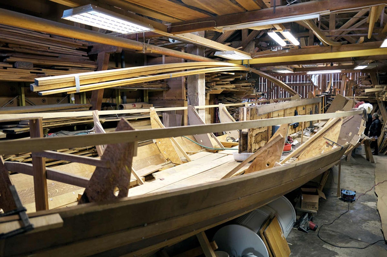 Werkstatt mit hölzernem Bootsbauprojekt und Holzlager