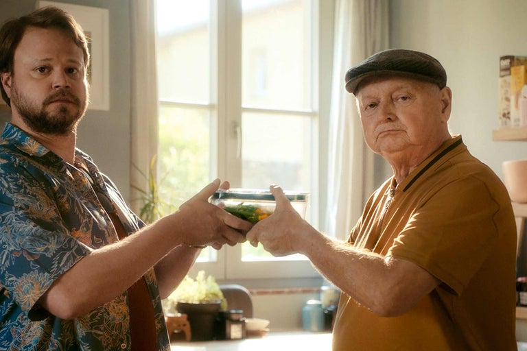 Deux personnes tiennent une boîte de conservation contenant des aliments.