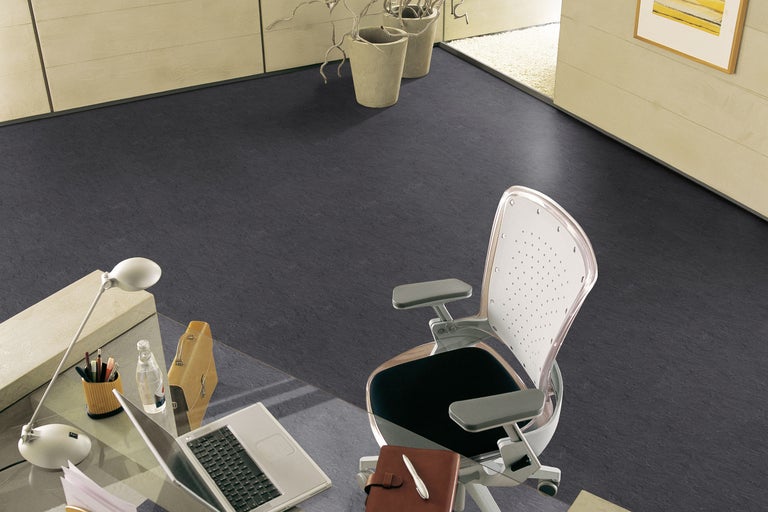 Espace de bureau avec revêtement de sol foncé, bureau et chaise de bureau