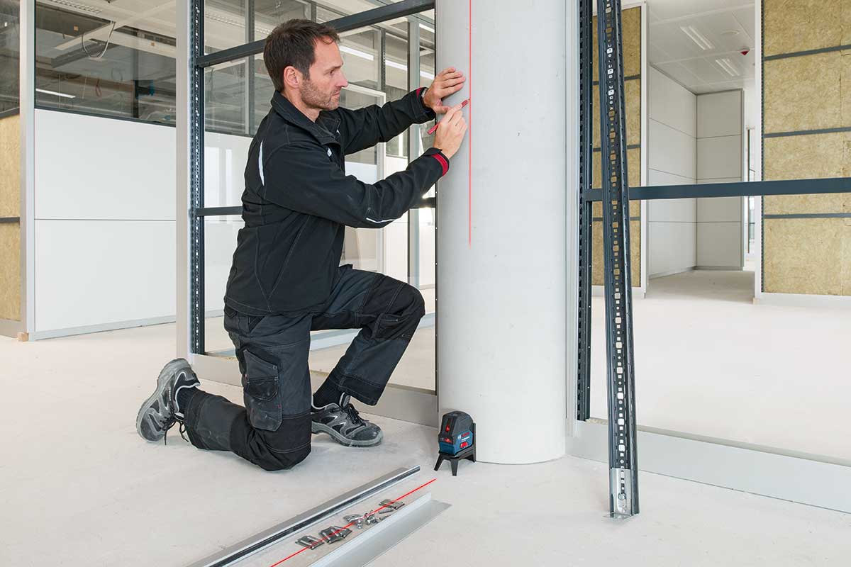 Artisan marquant une ligne au laser sur une colonne pour l'aménagement intérieur
