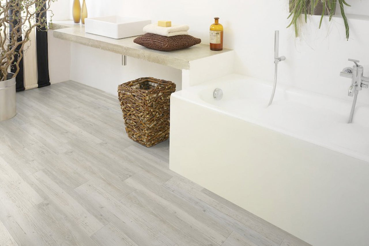 Badezimmer mit Badewanne, Waschbecken und hellem Holzboden