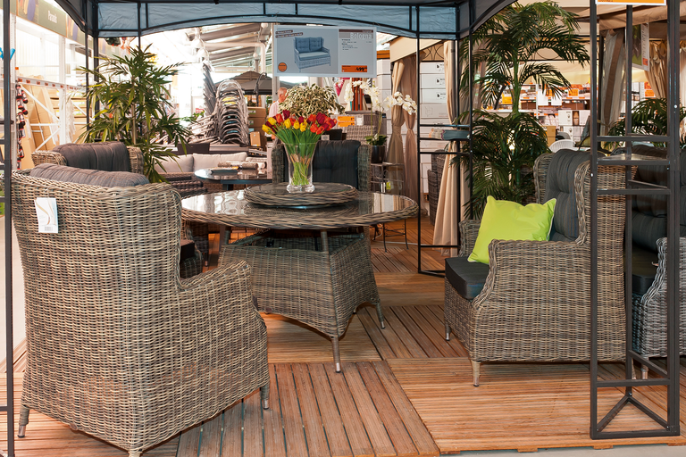Salon de jardin avec fauteuils en rotin et table ronde sous un pavillon.