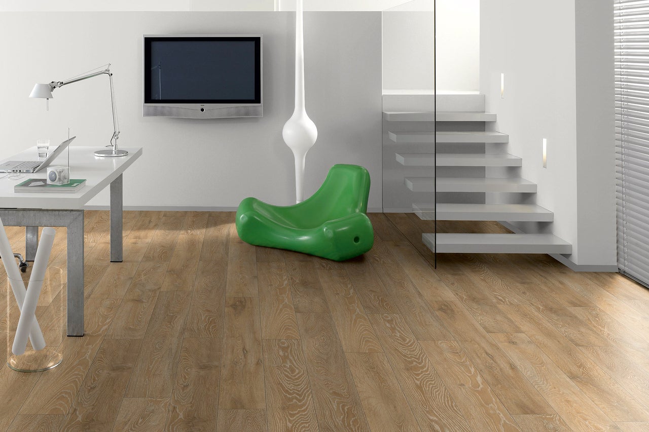 Heller Wohnraum mit Schreibtisch, Fernseher, Treppe und Laminatboden.