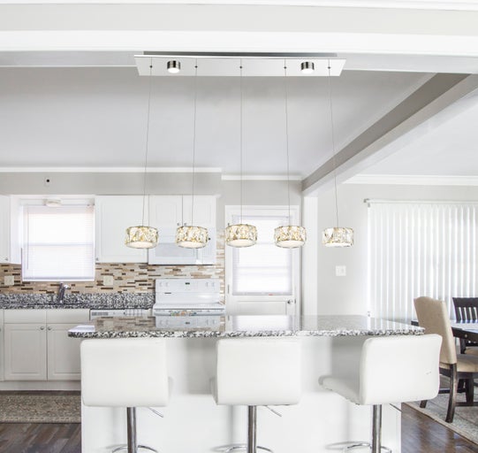 Helle Küche mit Kücheninsel, Barhockern und Hängelampe mit fünf Leuchten