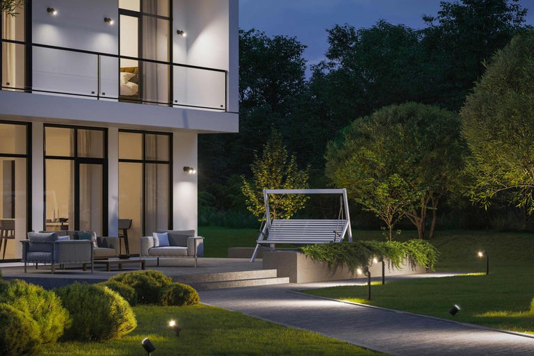 Aussenansicht eines modernen Hauses mit Gartenbeleuchtung, Gartenmöbeln und einer Schaukel