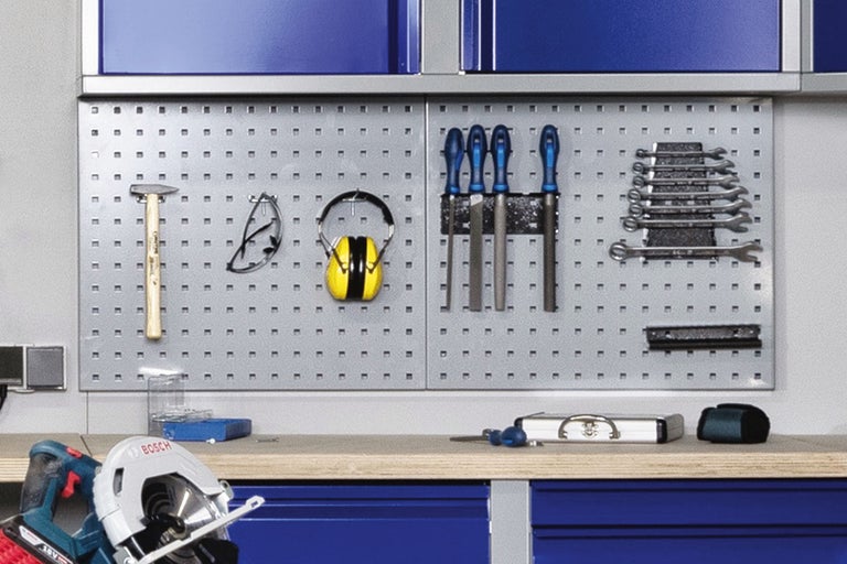 Atelier avec panneau à outils et divers outils tels que marteau, limes, clés et protection auditive