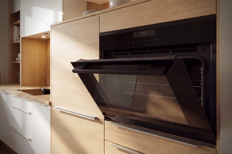 Four encastrable avec porte ouverte dans une cuisine moderne avec façades en bois et éléments blancs.