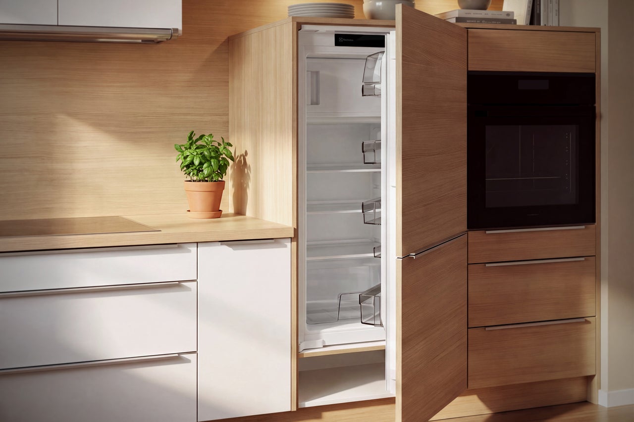 Cuisine équipée moderne avec réfrigérateur Electrolux, façades en bois clair et four encastré, environnement de cuisine lumineux et ordonné.