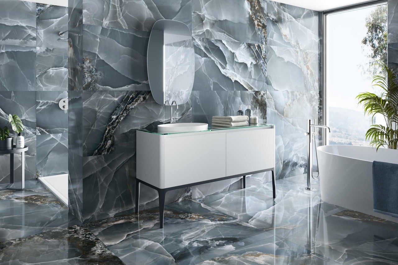 Salle de bains moderne avec carrelage en onyx sur les murs et le sol, meuble-lavabo et baignoire.