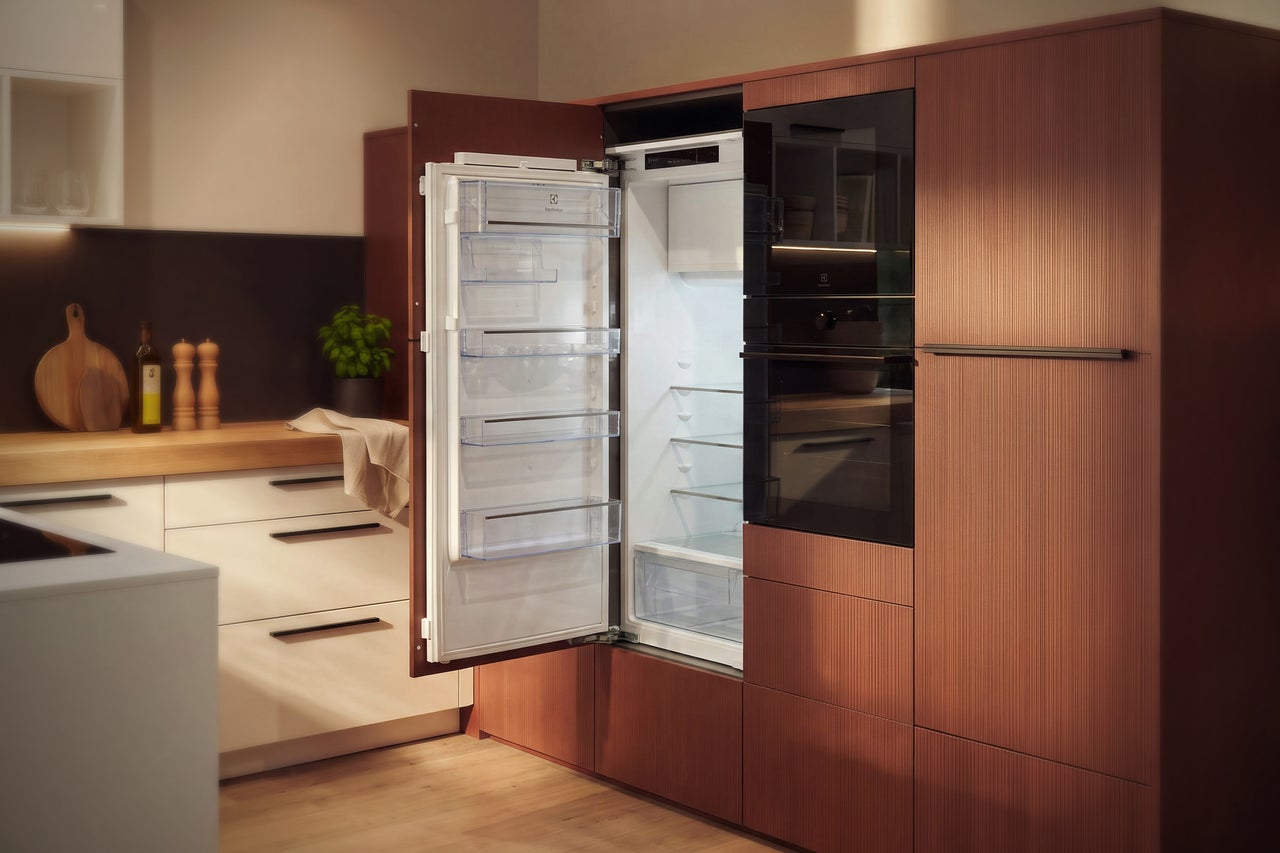 Cuisine équipée moderne avec réfrigérateur encastrable Electrolux et four intégrés dans une ambiance chaleureuse.