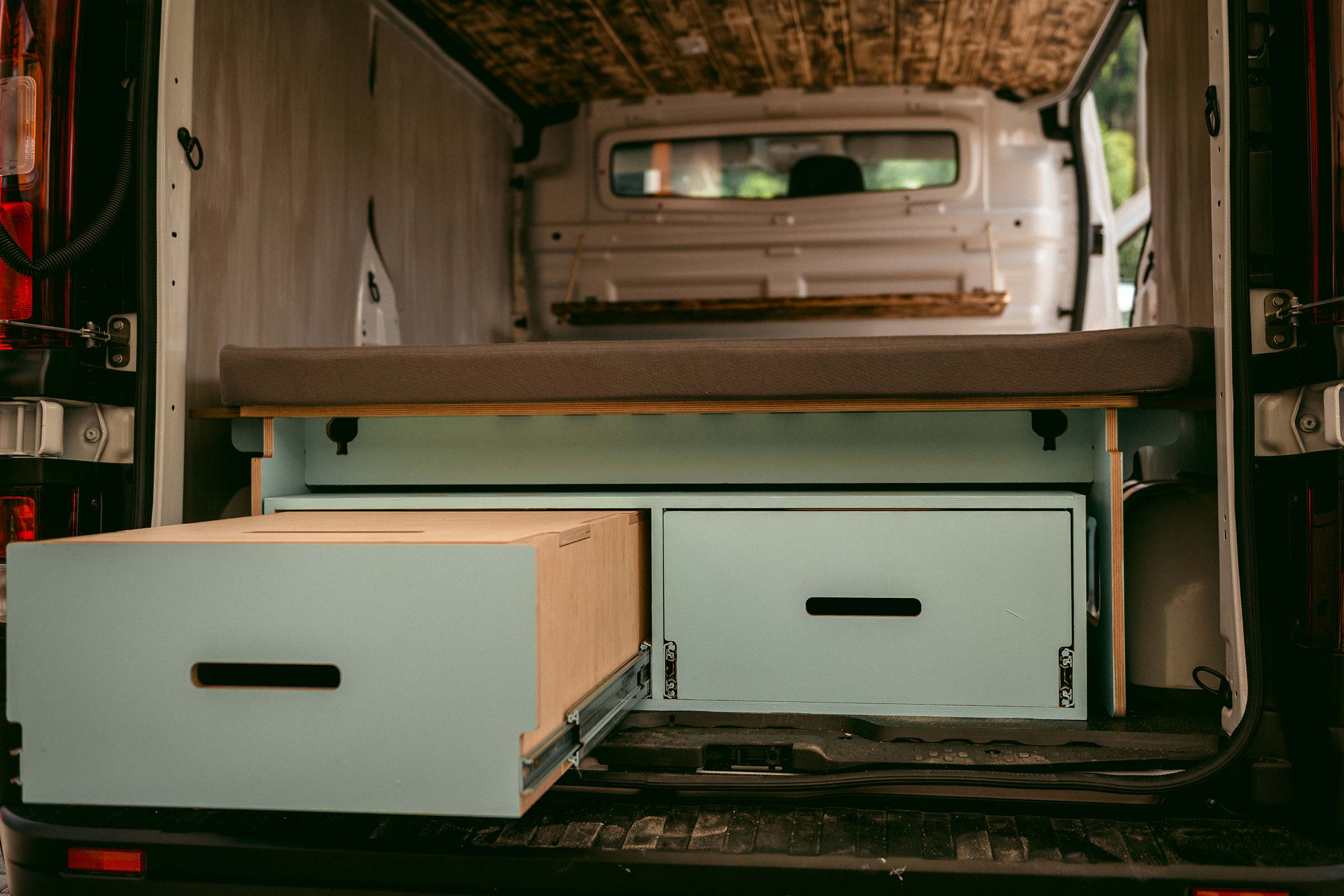 Aménagement intérieur d'un van avec tiroirs et lit