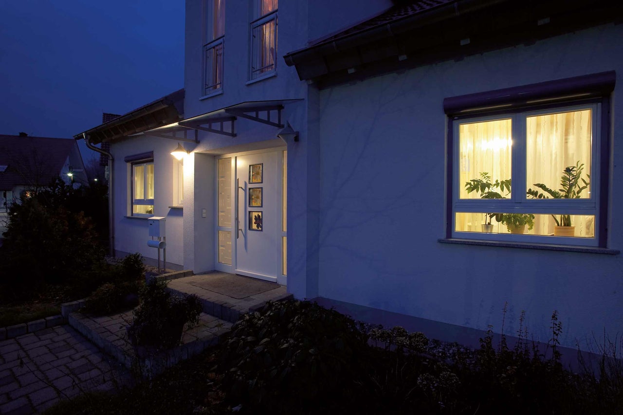 Façade de maison avec porte d'entrée, fenêtres et volets roulants au crépuscule
