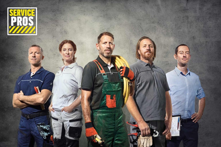 Un groupe d'artisans de Hornbach Service Pros se tient devant un mur gris.