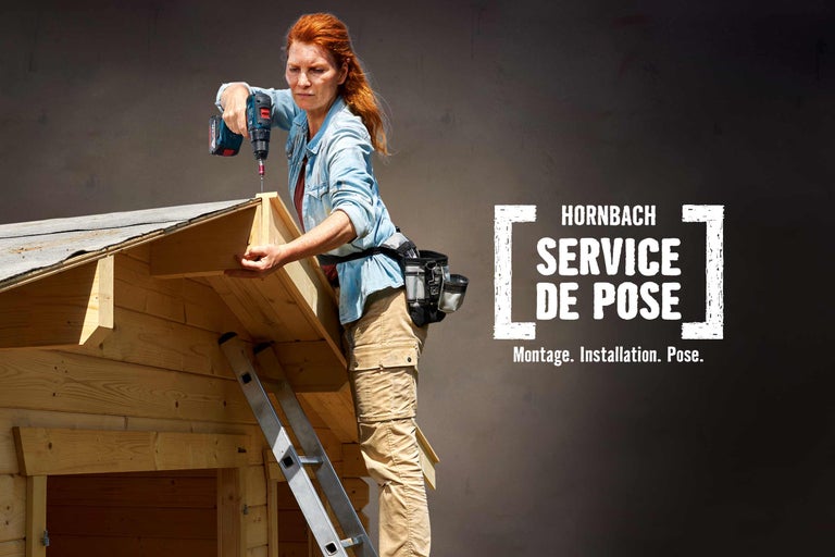 Une femme assemble une maison en bois avec un tournevis sans fil. Service de montage Hornbach.