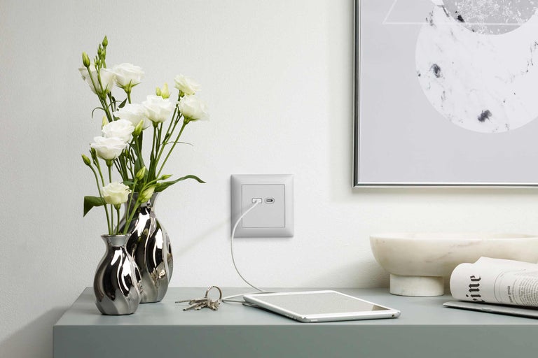 Photo d'intérieur d'une pièce avec une prise de courant avec port USB, une tablette, des clés et un vase de fleurs