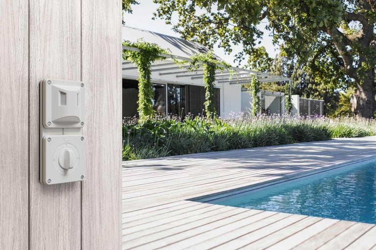 Scène avec détecteur de mouvement et interrupteur sur un mur en bois près d'une piscine