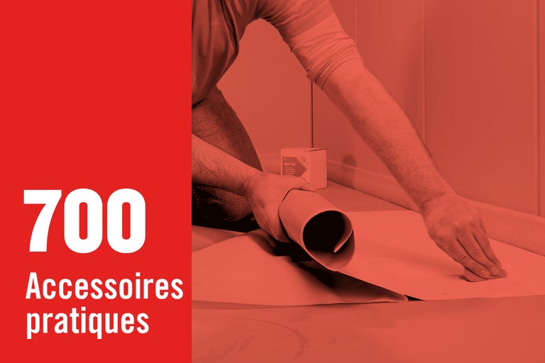 Une personne déroule un revêtement de sol, à côté se trouve un paquet d'accessoires.