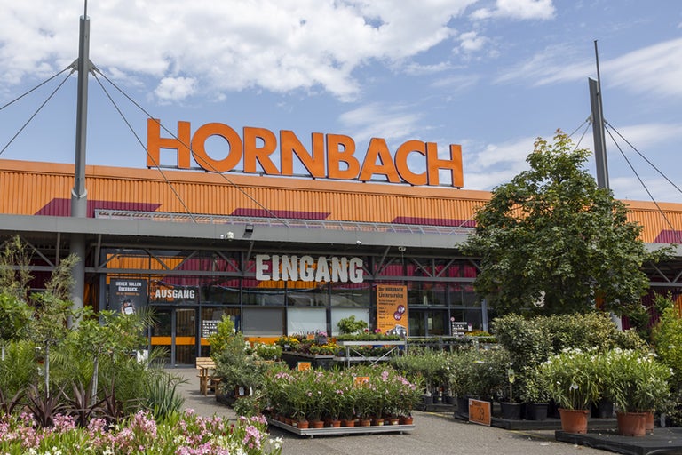 Vue extérieure d'un magasin de bricolage Hornbach avec des plantes devant l'entrée