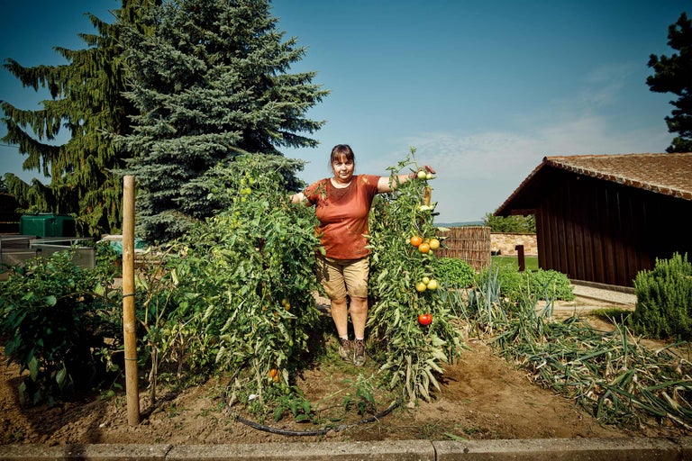 Une femme se tient dans un potager au milieu de plants de tomates.