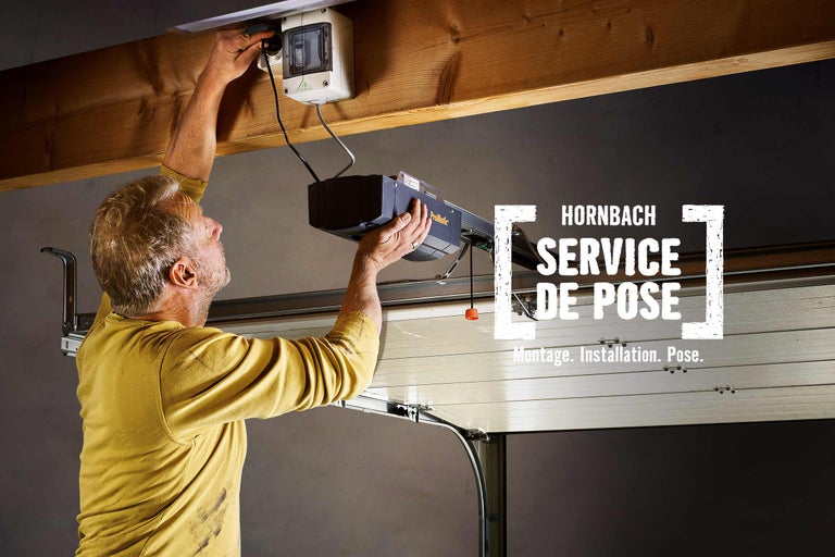 Un homme installe un ouvre-porte de garage. Service de montage Hornbach.