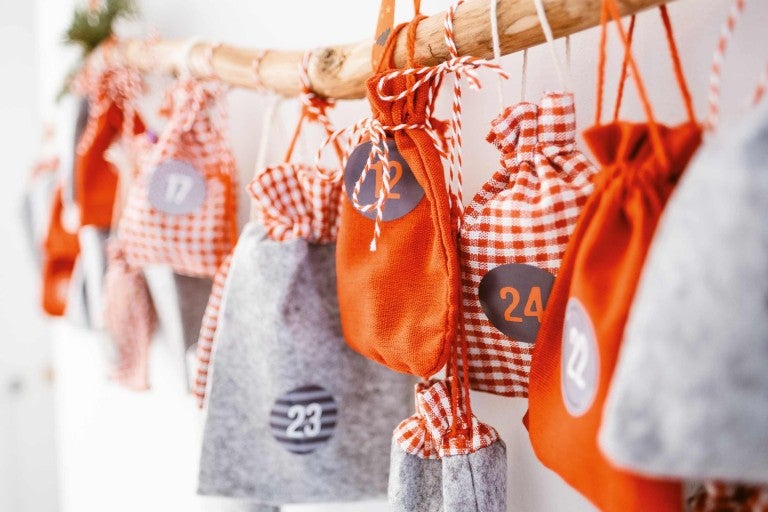 Calendrier de l'Avent avec sacs en tissu numérotés sur une branche
