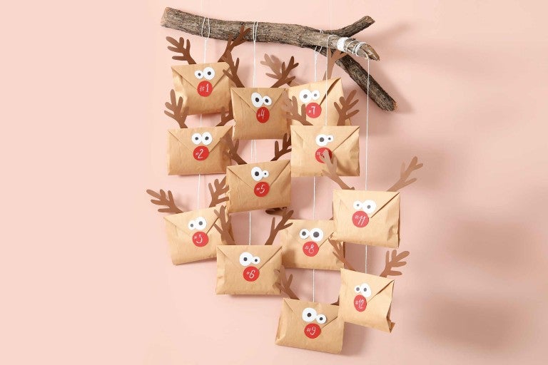 Calendrier de l'Avent avec des enveloppes en papier, des numéros et des bois suspendus à une branche
