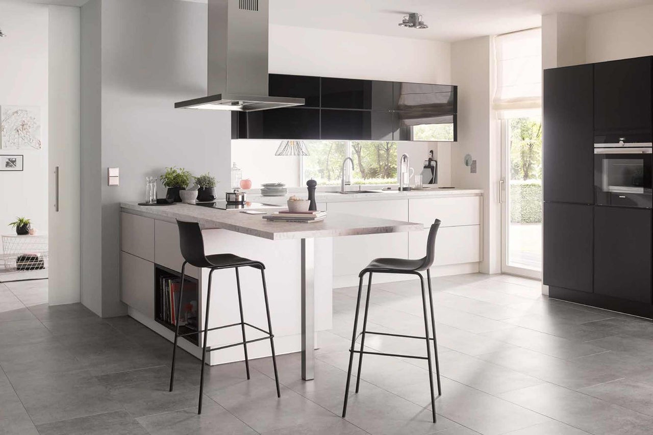 Cuisine moderne avec îlot de cuisine, hotte aspirante et tabourets de bar.