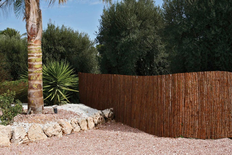 Gartenszene mit Sichtschutzzaun aus Naturmaterialien, Steinen und Pflanzen