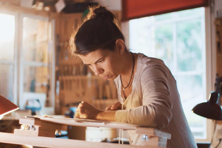Frau arbeitet in einer Werkstatt mit Holzbearbeitungswerkzeugen