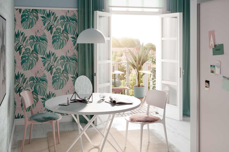 Pièce lumineuse avec papier peint Monstera, table blanche, chaises, miroir et décoration pour une ambiance conviviale.