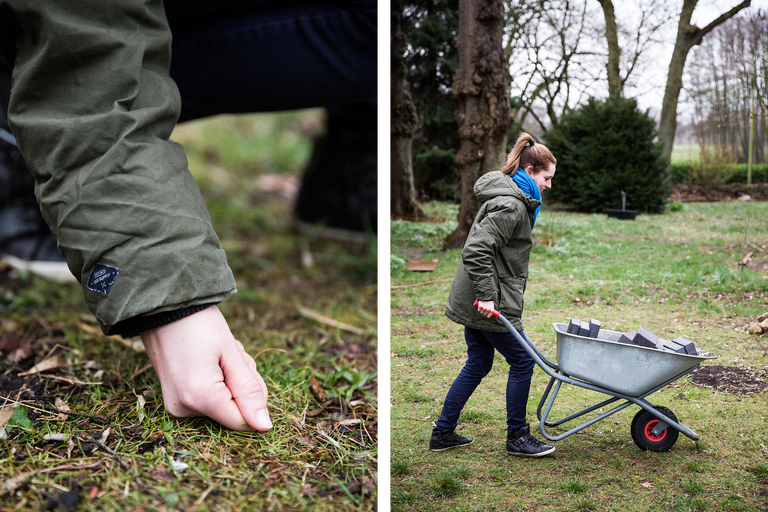 Une femme transporte des pierres avec une brouette dans un jardin.