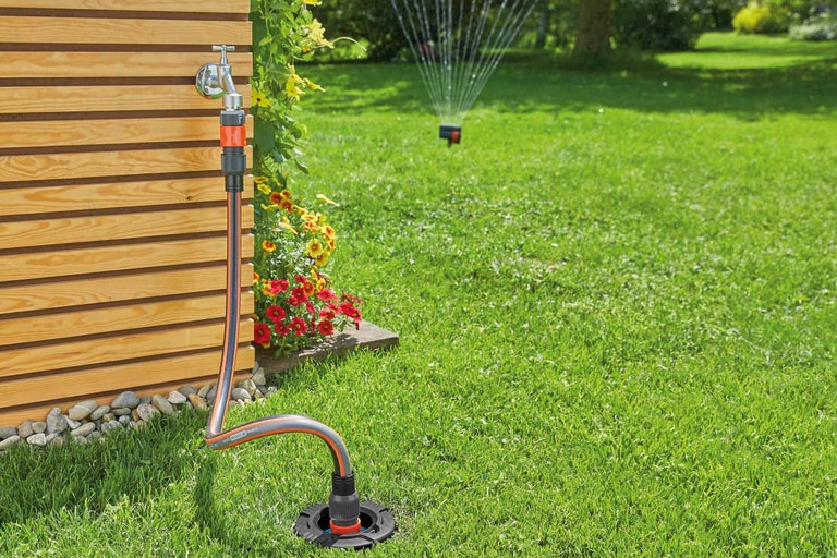 Scène de jardin avec robinet, raccord de tuyau, tuyau d'arrosage et arroseur de gazon