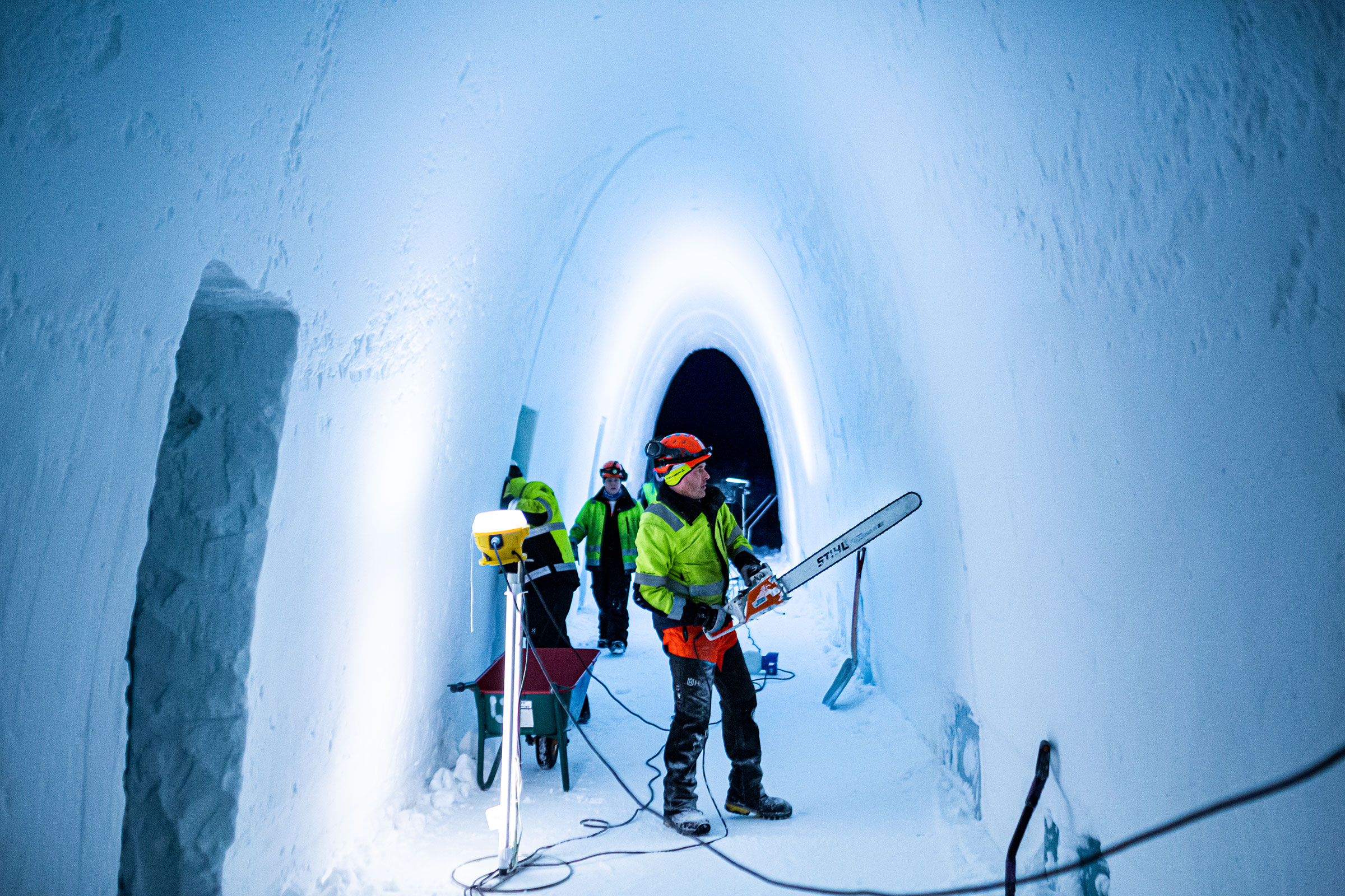 Person arbeitet mit einer Kettensäge in einem Tunnel aus Schnee.