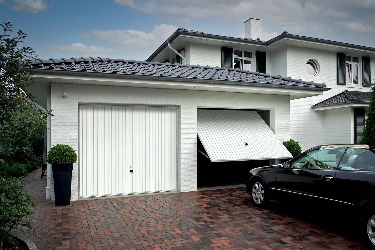 Garage avec porte sectionnelle, partiellement ouverte avec voiture devant