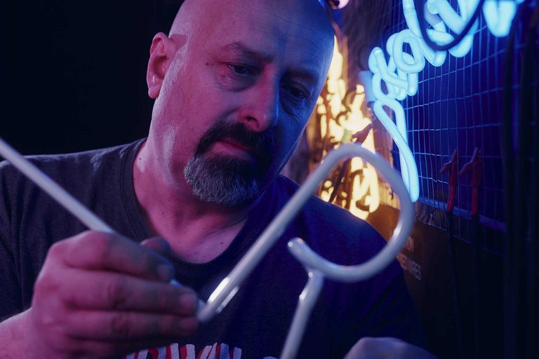 Un homme fabrique une enseigne lumineuse.