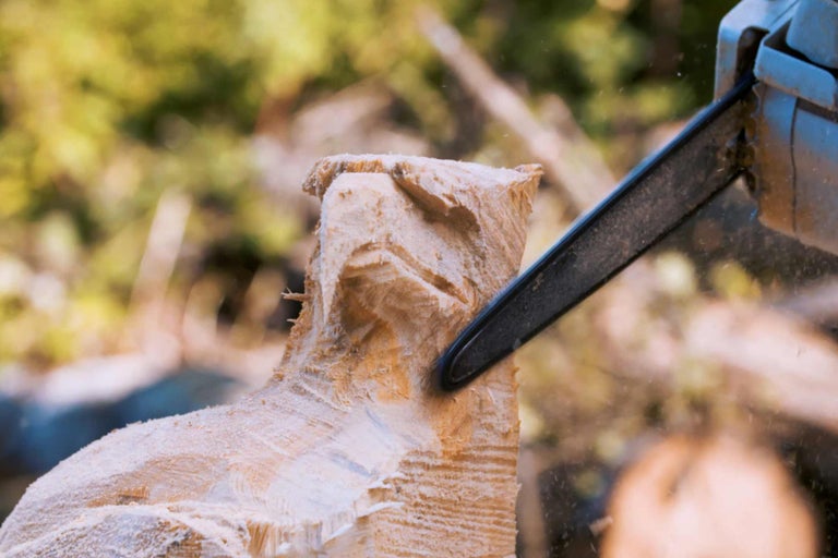 Une sculpture en bois est travaillée avec une tronçonneuse.