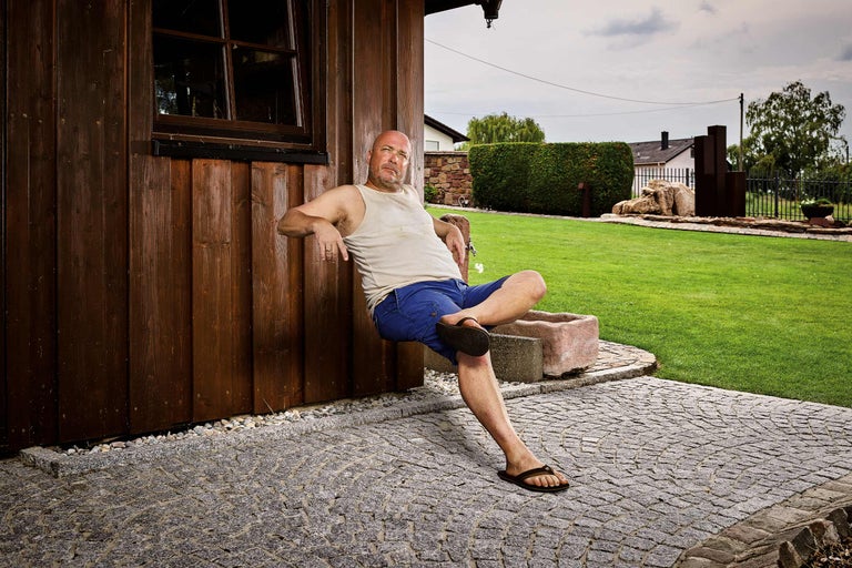Homme assis contre un mur en bois avec pavage en granit dans le jardin