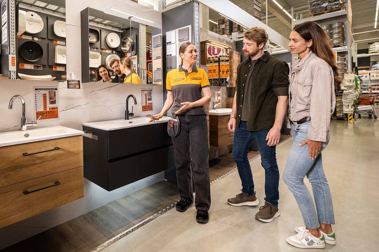 Trois personnes sont assises à une table devant deux écrans et discutent d'un projet chez Hornbach.