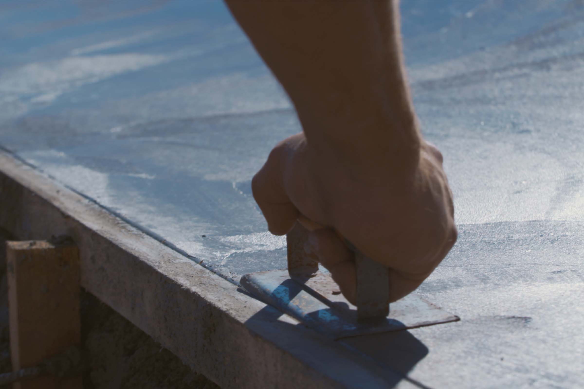 Main lissant le béton à la truelle