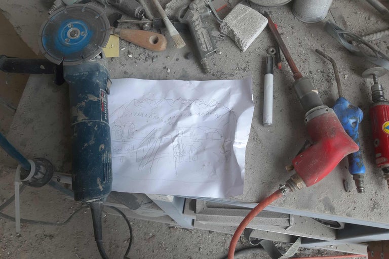 Une meuleuse, un croquis et d'autres outils sur un établi.