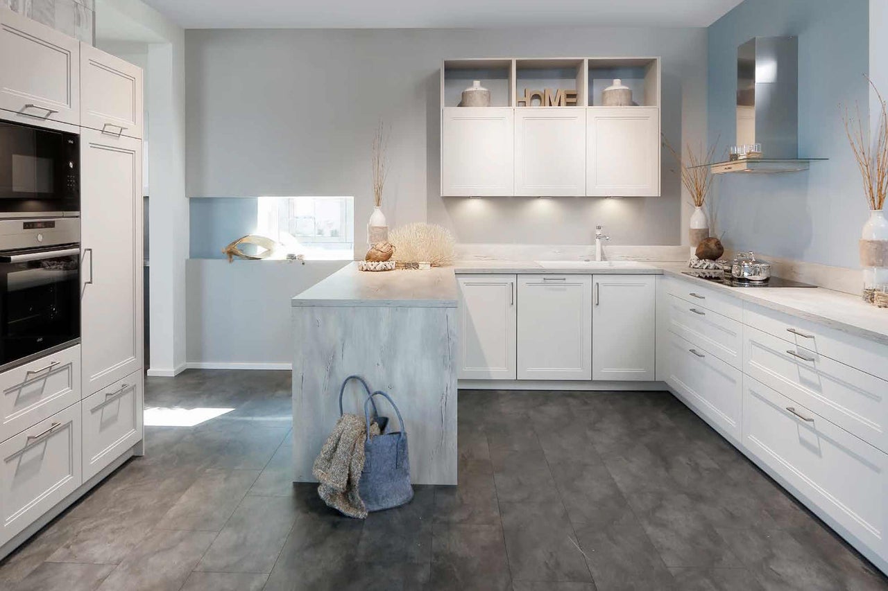 Cuisine claire avec armoires blanches, îlot de cuisine et appareils modernes.