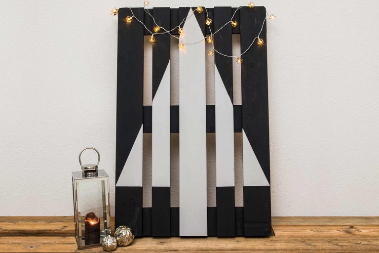 Dekoratives Holzbrett mit Tannenbaumdesign, Lichterkette und Kerzenlaterne für festliche Atmosphäre