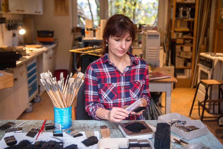 Femme nettoyant un pinceau dans un atelier avec du matériel de travail
